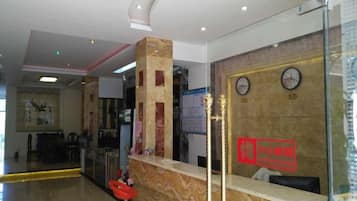 A reception area with a marble counter, a clock, and a glass partition.