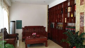 Un salon avec un canapé en bois, une table basse, une bibliothèque et une plante en pot.
