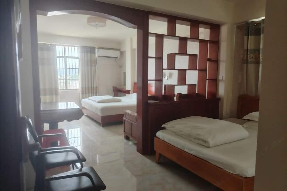 Habitación de hotel con cama, escritorio, silla, armario y ventana.