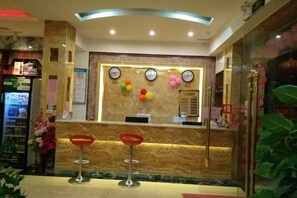 A reception area with a marble counter, two red bar stools, and a clock. - Chongzuo Aloft Convenience Hotel (Chongzuo)