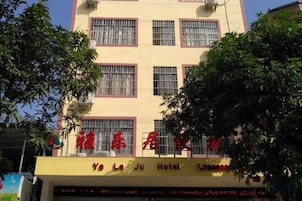 A hotel with a yellow facade, multiple windows, and a sign with red lettering.