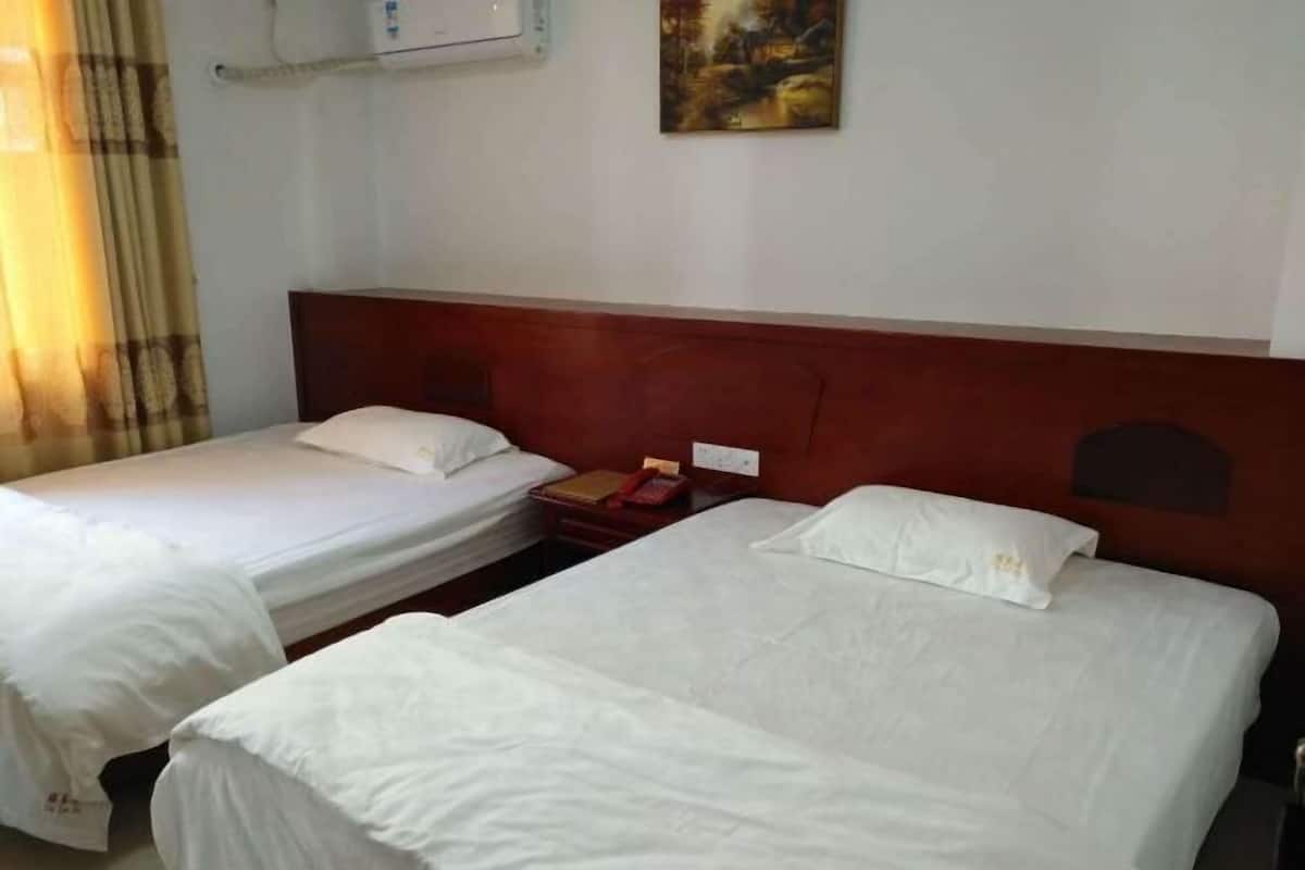Habitación de hotel con dos camas individuales, cabecera de madera, un cuadro en la pared y una ventana con cortinas.