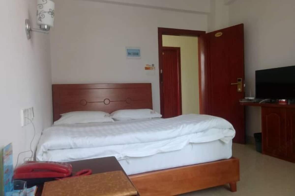 Una habitación de hotel con una cama de madera, un televisor y un escritorio con teléfono.