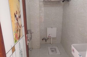 A bathroom with a toilet, a sink, and a shower area.