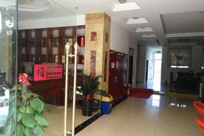 A hotel lobby with a reception desk, a pillar, and a red carpet leading to the entrance. - Chongzuo Aloft Convenience Hotel (Chongzuo)