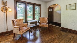 A room with wooden flooring, two upholstered chairs, a table, and a lamp. - Spacious group getaway with heated pool, sauna, basketball court, and firepit. Sleeps up to 15 guests and is just minutes from Lake Michigan beaches and downtown St. Joseph. Perfect for family vacations, group trips, and relaxing Southwest Michigan. (Benton Harbor)