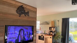 Eine moderne Küche mit Einbauofen, Mikrowelle und Geschirrspüler. Ein Flachbildfernseher ist an einer Holzwand über der Arbeitsfläche angebracht.