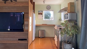 Eine kompakte Küche mit Holzschränken, einem integrierten Fernseher, einer Uhr und einem Fenster.
