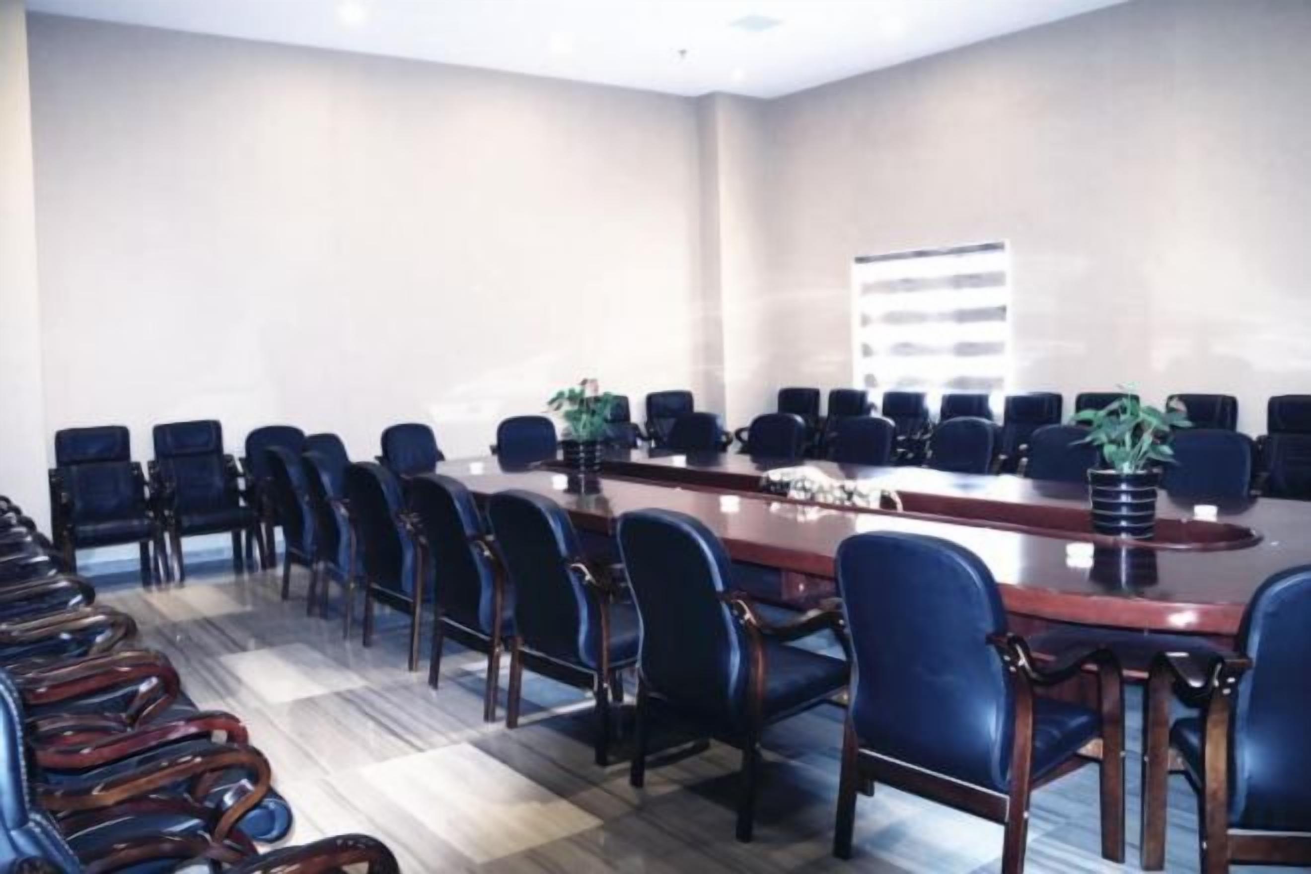 Una sala de conferencias con una mesa larga, varias sillas y una planta en maceta.