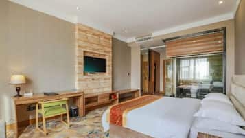 A hotel room with a bed, a desk, a television, and a sliding door to a balcony.