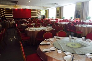 Ein Banketthaus mit runden Tischen, die zum Essen gedeckt sind, roten Stühlen und einem mit rotem Teppich ausgelegten Boden.