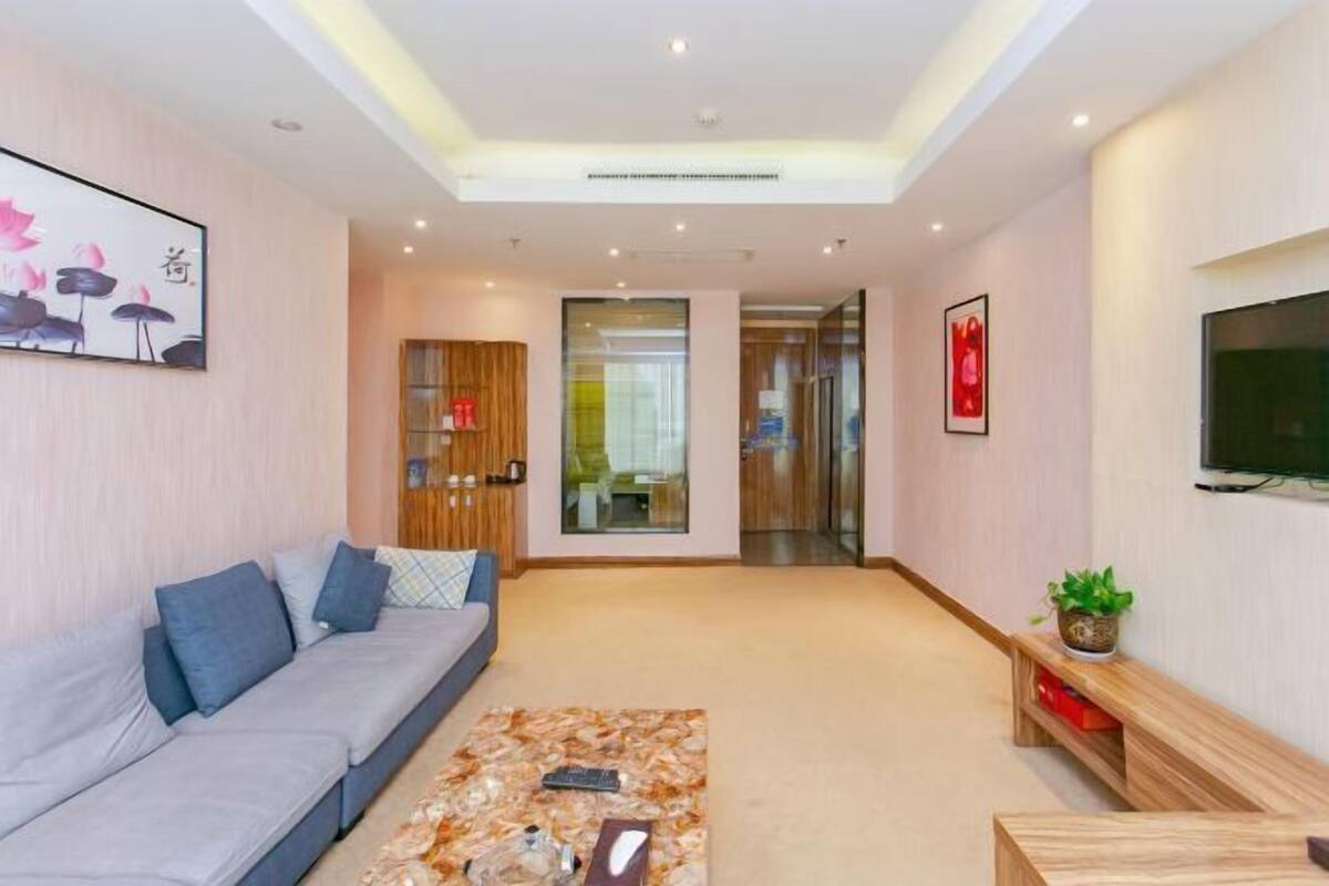 Een moderne woonkamer met een bank, salontafel en een aan de muur bevestigde televisie.