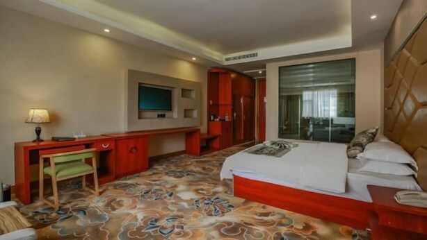 Ein Hotelzimmer mit Bett, Schreibtisch, Stuhl, Fernseher und Kleiderschrank.