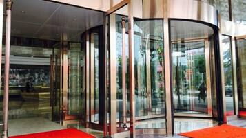 A revolving door with glass panels, a red carpet, and a marble floor.