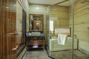 A modern bathroom with a glass shower enclosure, a wooden vanity, and a large mirror.
