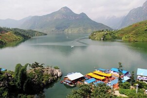 Vista a un lago con un pequeño muelle y edificios con tejados azules.