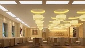 Un hall d’hôtel doté de plusieurs espaces salon, de grands lustres et d’un tapis à motifs.