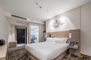 Quarto de hotel moderno com uma cama grande, uma mesa de cabeceira com telefone e uma obra de arte na parede.