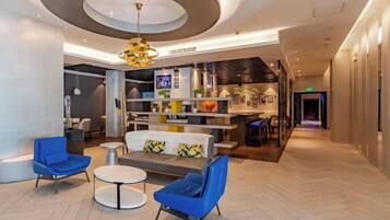 Un vestíbulo moderno con zona de estar, mostrador de recepción y un bar-lounge.
