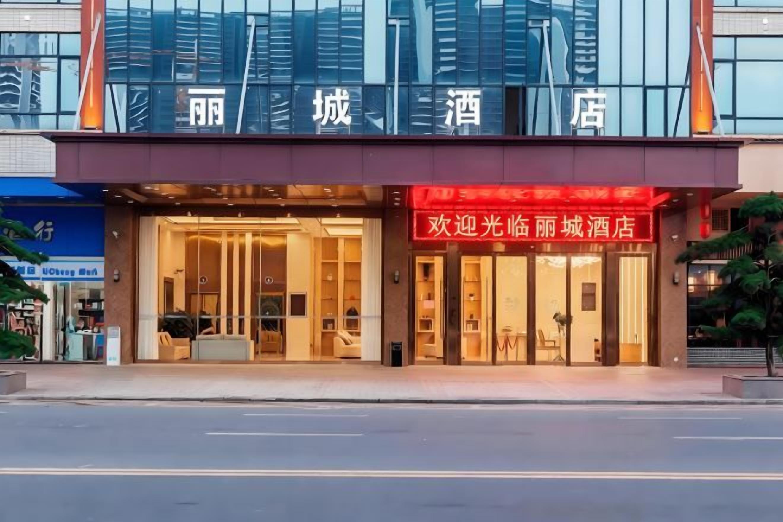 A hotel with a modern facade, large glass windows, and a prominent red sign.