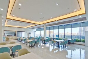 A modern dining area with tables and chairs, large windows, and a city view. - Licheng Hotel (Zhongshan Xiaolan High-speed Railway Dongsheng Station Branch) (Zhongshan)