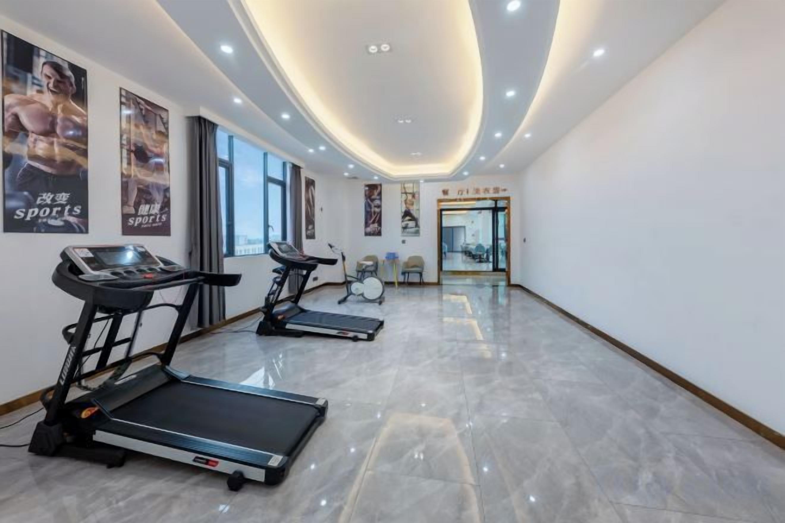 Un gimnasio con cintas de correr, una bicicleta estática de pared y un espejo.