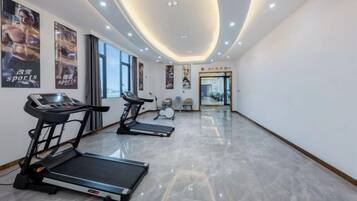 Un gimnasio con cintas de correr, una bicicleta estática de pared y un espejo.