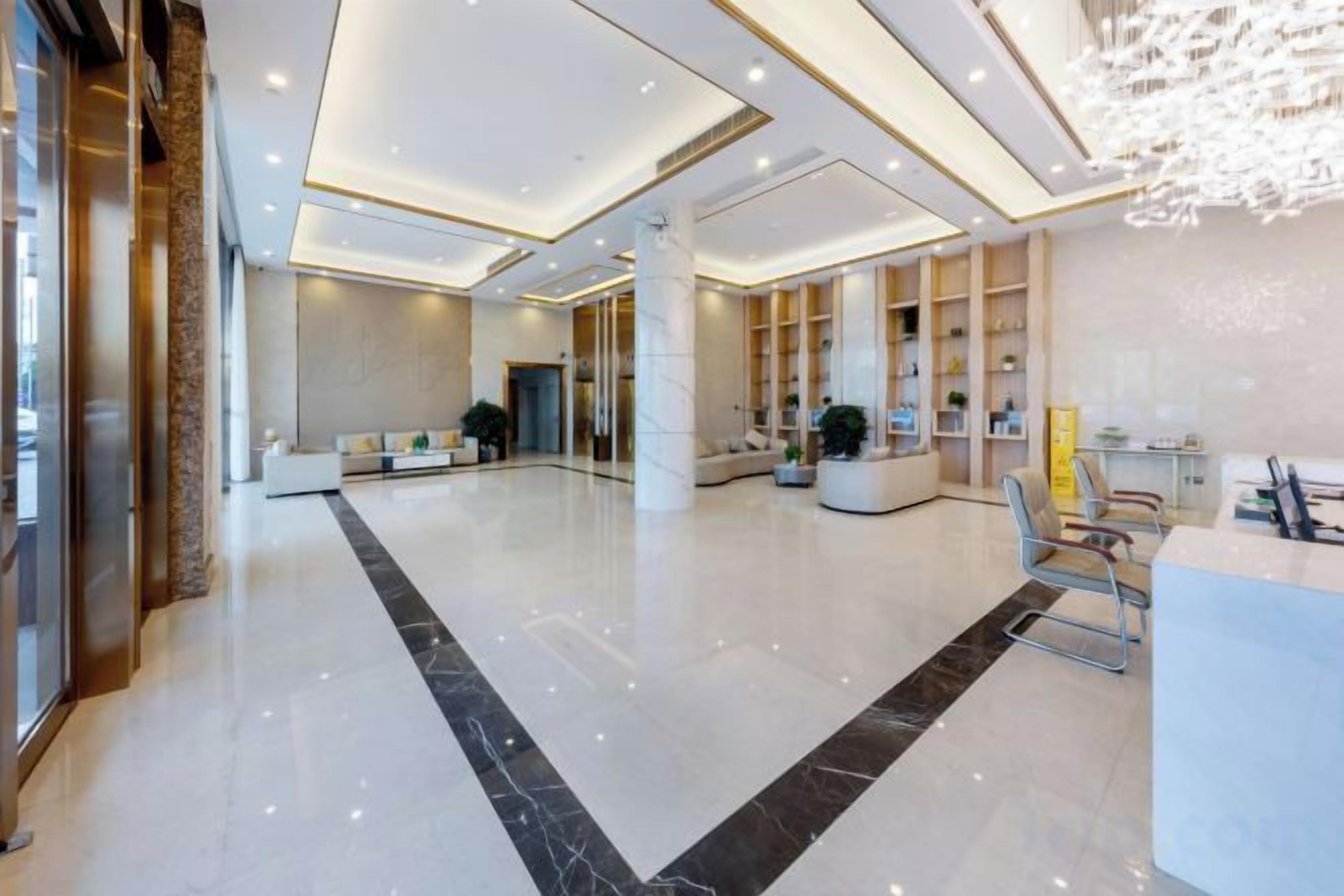 A spacious lobby with a reception desk, seating area, and a large chandelier.