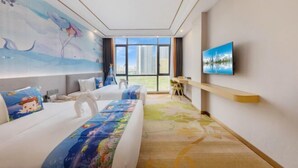 Una habitación de hotel con un ventanal grande, una cama con colcha colorida, un escritorio y un televisor montado.