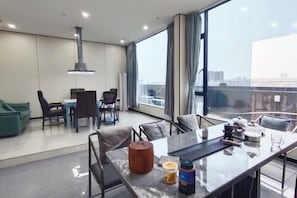 Et moderne hotelværelse med spiseplads, store vinduer og udsigt over byen.
