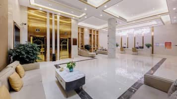 A spacious lobby with a reception desk, seating area, and a large plant.