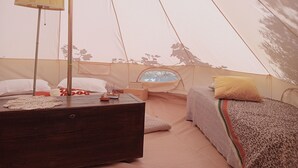 Una carpa con cama, un cofre de madera y una mesita con un modelo de barco.