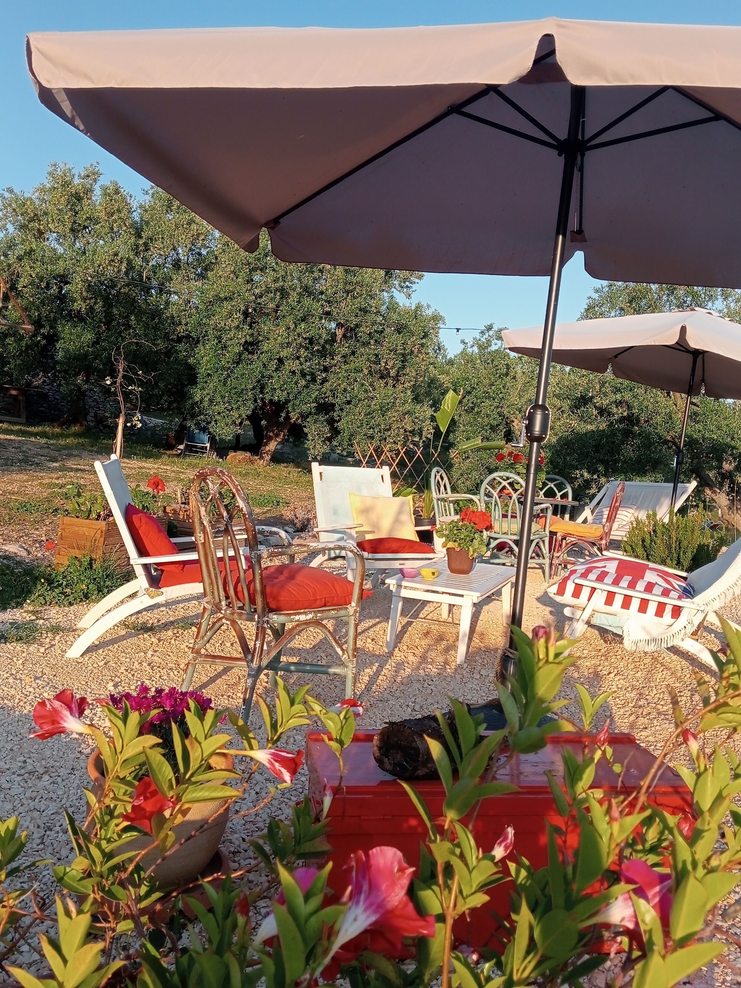 Un área de estar al aire libre con sillones de descanso y una mesa bajo un paraguas grande.
