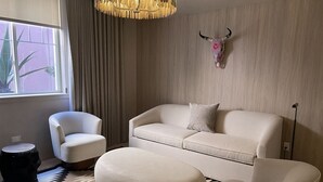 A modern living room with a sofa, armchairs, a round ottoman, a decorative bull skull, and a patterned rug.