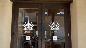 Una doble puerta de madera con el número '105' encima, que da a un edificio con un cartel que dice 'PALACE Boutique Hotel' y 'Seth Anderson Studio Gallery'.