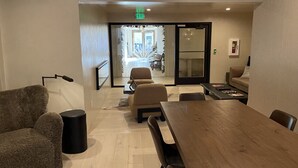 A modern meeting room with a wooden table, comfortable seating, and a glass door leading to an outdoor area. - Palace Modern Hotel at the Plaza - Patio King 10 (Santa Fe)