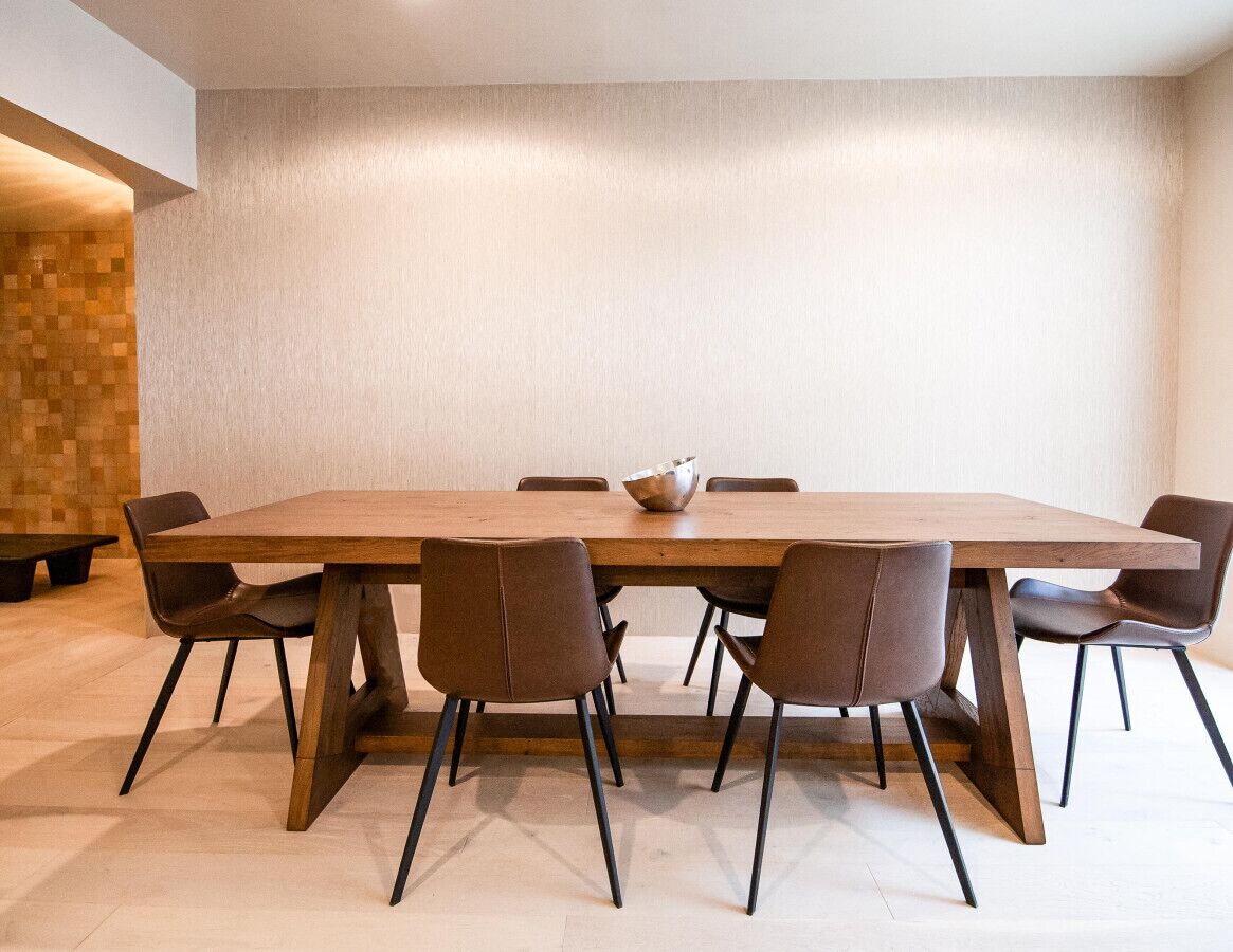 A modern dining area with a long wooden table, six brown chairs, and a central bowl.