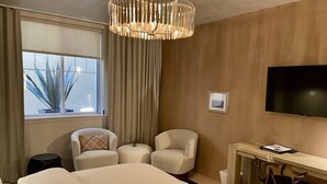 Ein Hotelzimmer mit einem großen Bett, zwei Sesseln, einem Schreibtisch und einem Fernseher.