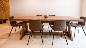 Un'area pranzo moderna con un lungo tavolo di legno, sei sedie marroni e una ciotola al centro.