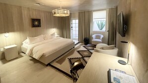 Una habitación de hotel moderna con una cama grande, un escritorio, una silla y un televisor.