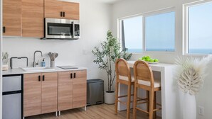 Eine moderne Küche mit Holzschränken, einer Edelstahl-Mikrowelle, einem Spülbecken und einem Essbereich mit zwei Stühlen.