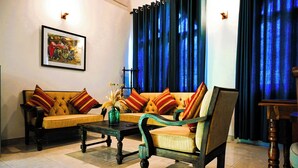 A living room with a sofa, armchair, and coffee table. There is a framed picture on the wall and a vase with dried plants on the coffee table. - Paradise Holiday Village (Negombo)