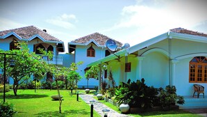 A two-story building with a tiled roof, satellite dish, and a small garden area with potted plants and a pathway. - Paradise Holiday Village (Negombo)