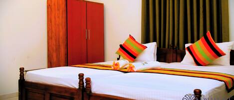 Una cama bien hecha con almohadones a rayas, un armario de madera y una ventana con cortinas.