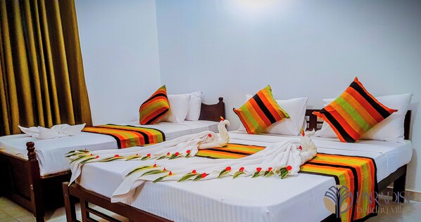 A hotel room with two beds, each with white linens, striped blankets, and colorful pillows. - Paradise Holiday Village (Negombo)