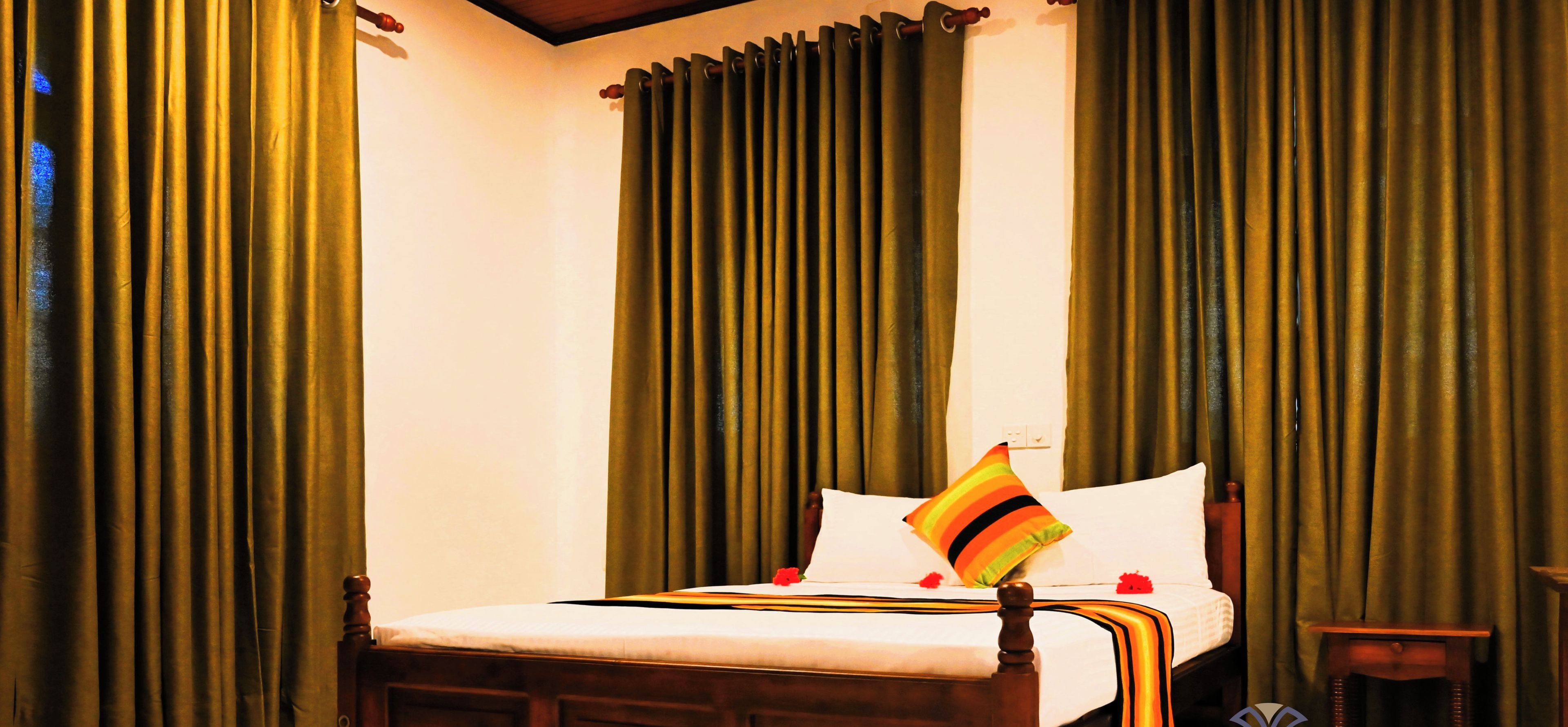 A bedroom with a wooden bed, green curtains, and a small bedside table.