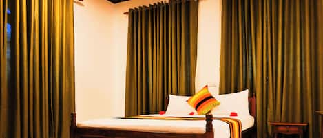 A bedroom with a wooden bed, green curtains, and a small bedside table.