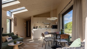 Un intérieur moderne comprenant un canapé, une table à manger, des chaises et un coin cuisine.