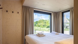 Une chambre avec un grand lit, un mur en bois et une fenêtre avec des rideaux.