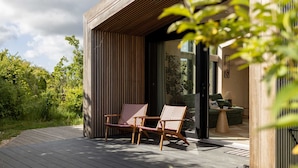Une terrasse extérieure moderne avec deux chaises en bois, un canapé et une petite table.